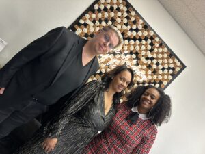 Zak, Crystal, and Tee stand in front of the Vegas Born Real Estate Services slogan, "Where life happens off the strip."