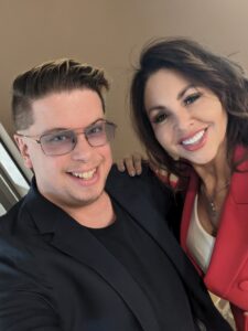 A close up selfie photo of Zak dressed in black and Merri dressed in bright red.