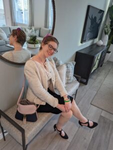 Dev sits, crossed leg, on a chair in a new home they are viewing.